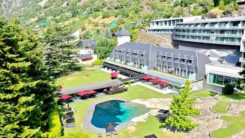 Un hotel con piscina, zona de estar al aire libre y vistas de las colinas circundantes.