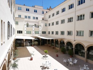 A hotel courtyard with multiple levels, outdoor seating, and potted plants. - TRH Ciudad de Baeza (Baeza)