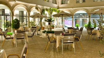 A hotel courtyard with outdoor seating, potted plants, and a patterned floor.