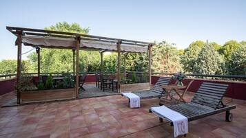Une terrasse sur le toit, aménagée avec des meubles en bois, une pergola et offrant une vue sur les arbres.
