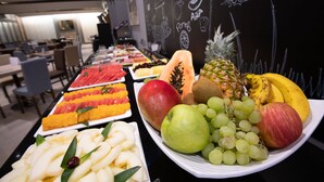A buffet table with various fruits and a chalkboard with fruit illustrations in the background. - Intelier Airén Hotel by Intelier Hotels & Suites (Alcazar de San Juan)