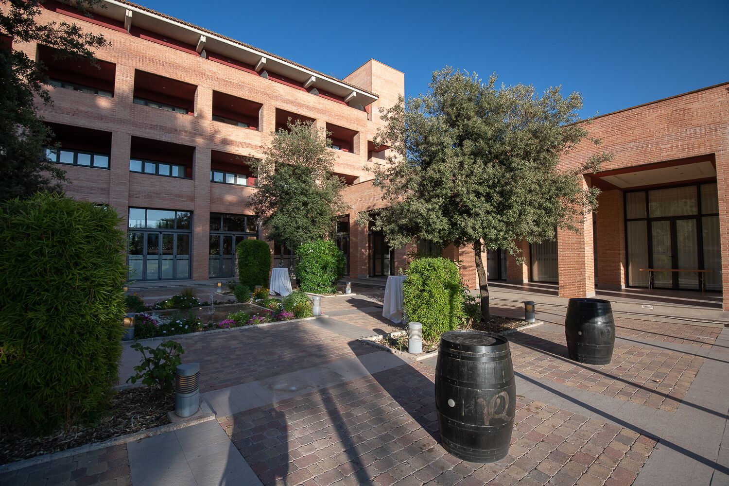 A courtyard with a brick building, trees, and outdoor seating.