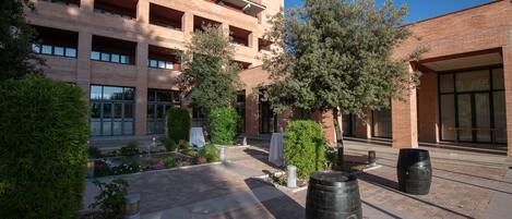 A courtyard with a brick building, trees, and outdoor seating.