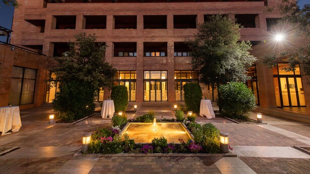 A hotel with a brick facade, multiple balconies, and a central courtyard with a fountain and tables. - Intelier Airén Hotel by Intelier Hotels & Suites (Alcazar de San Juan)