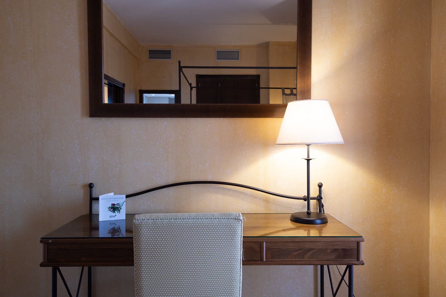 Een hotel bureau met een lamp, handdoek en spiegel.