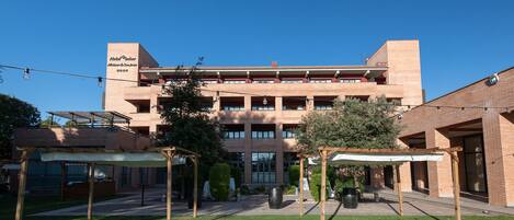 A multi-story hotel with a brick facade, outdoor seating areas, and a well-maintained lawn.