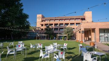 Un patio de hotel con mesas al aire libre y un edificio de ladrillo al fondo.