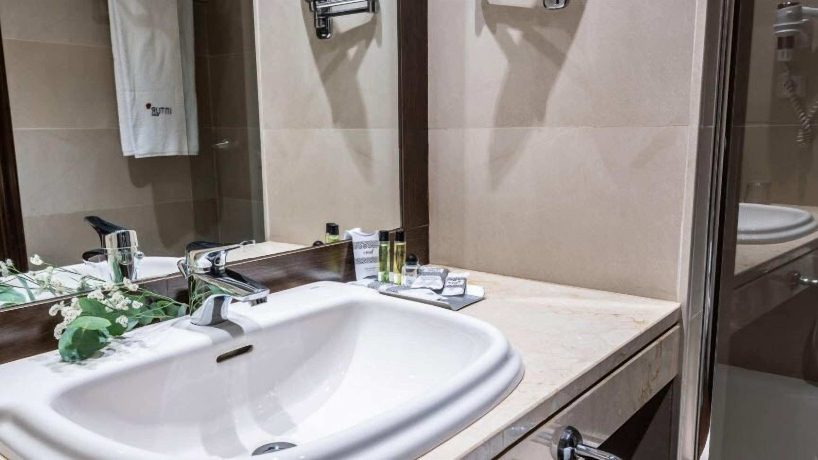 Un baño con un lavabo blanco, un espejo y artículos de tocador en la encimera.