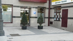 Entrada de hotel con un cartel de Zafiro Tours, acceso para sillas de ruedas y plantas en macetas.