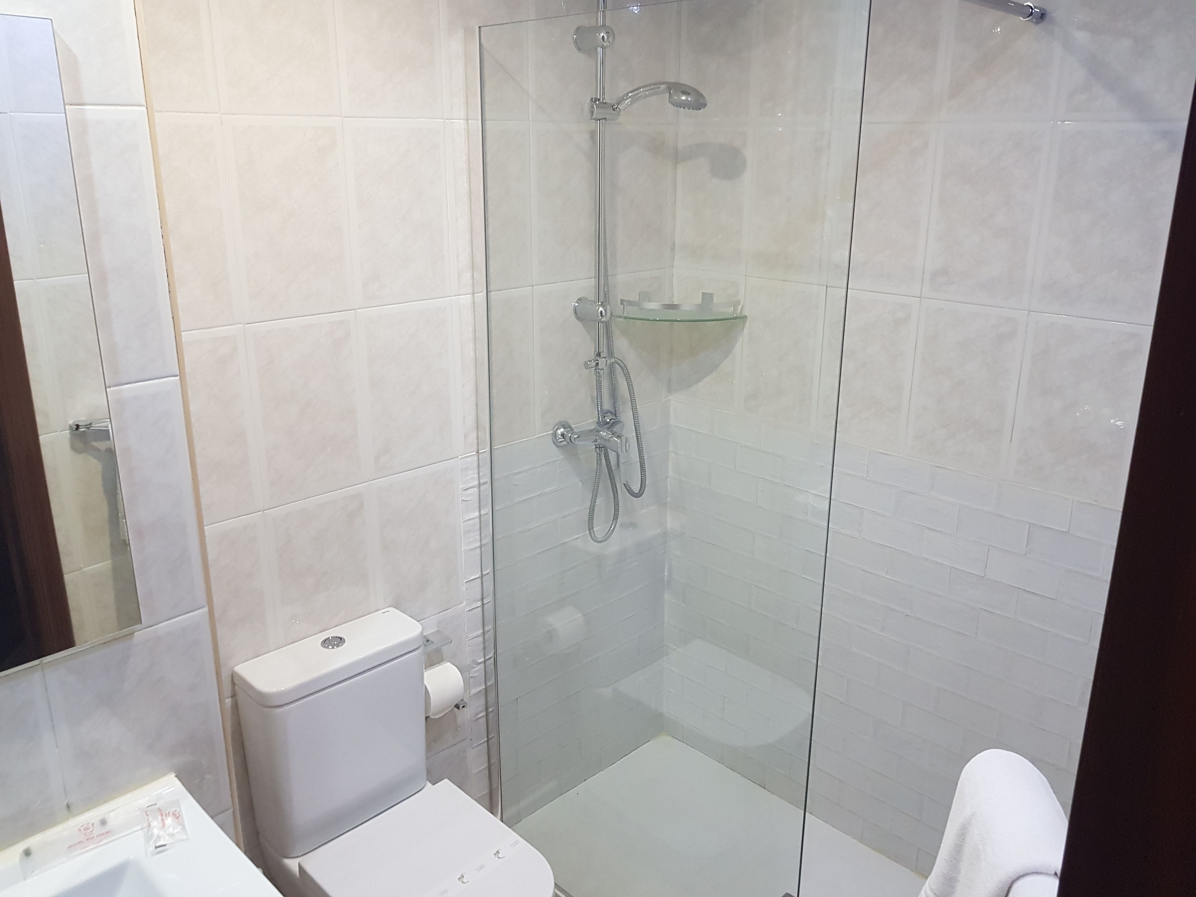 Une salle de bain moderne avec une douche à parois de verre, des toilettes blanches et un lavabo en verre.