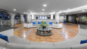 Un vestíbulo moderno con una mesa redonda central, zona de estar y mostrador de recepción.
