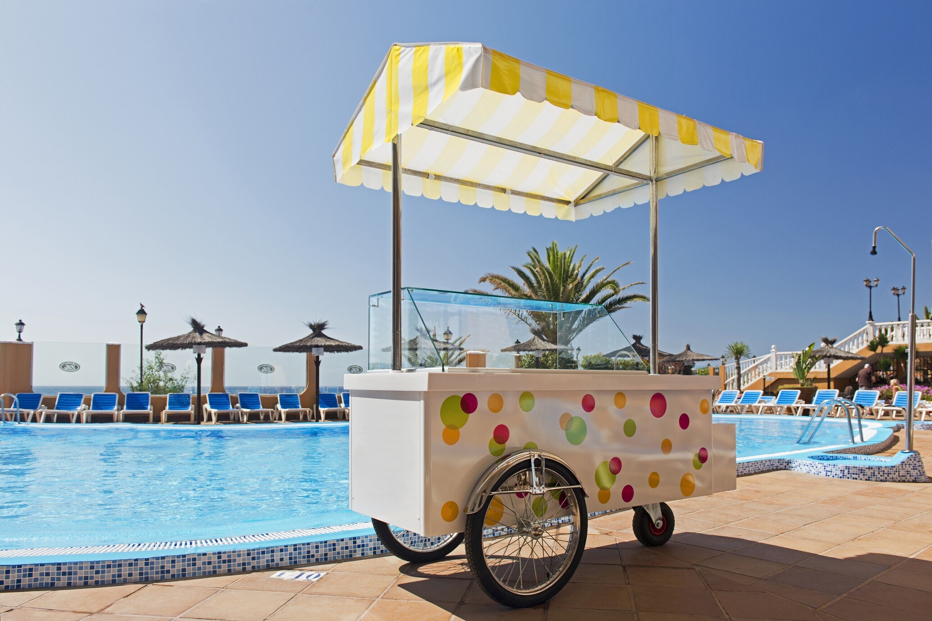 A poolside cart with a polka dot design, a canopy, and a glass enclosure.