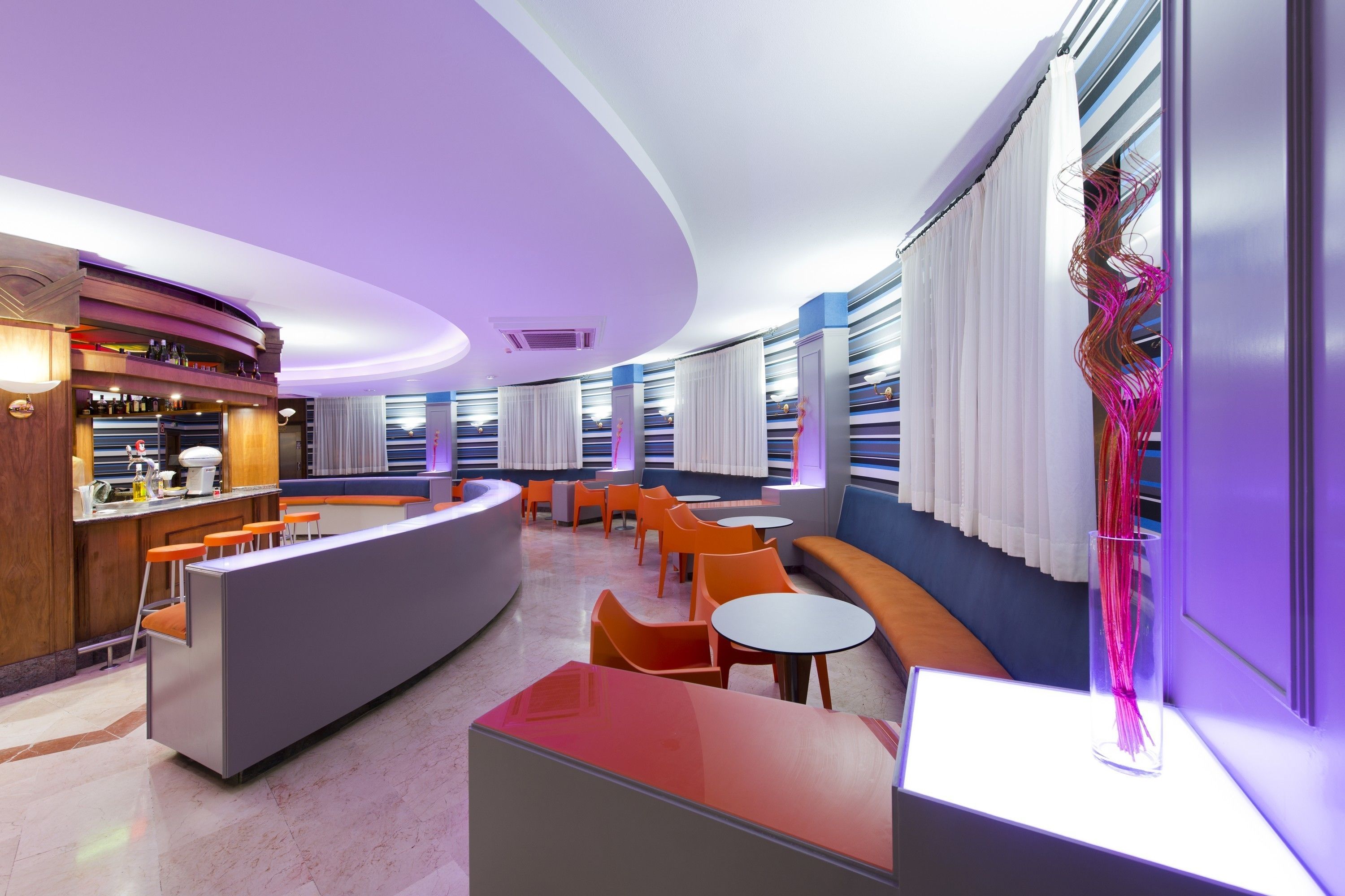 Un espace lounge moderne doté d’un bar incurvé, de différents types de sièges et d’une sculpture décorative.