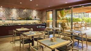 A restaurant with wooden tables and chairs, a counter with food and drinks, and a view of greenery outside. - The Moods Oasis (Barcelona)
