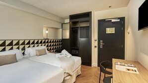A hotel room with a bed, a desk, a chair, a wardrobe, and a television. - The Moods Oasis (Barcelona)