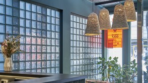A modern reception area with a dark tiled counter, large windows with a grid pattern, and hanging woven light fixtures. - The Moods Oasis (Barcelona)