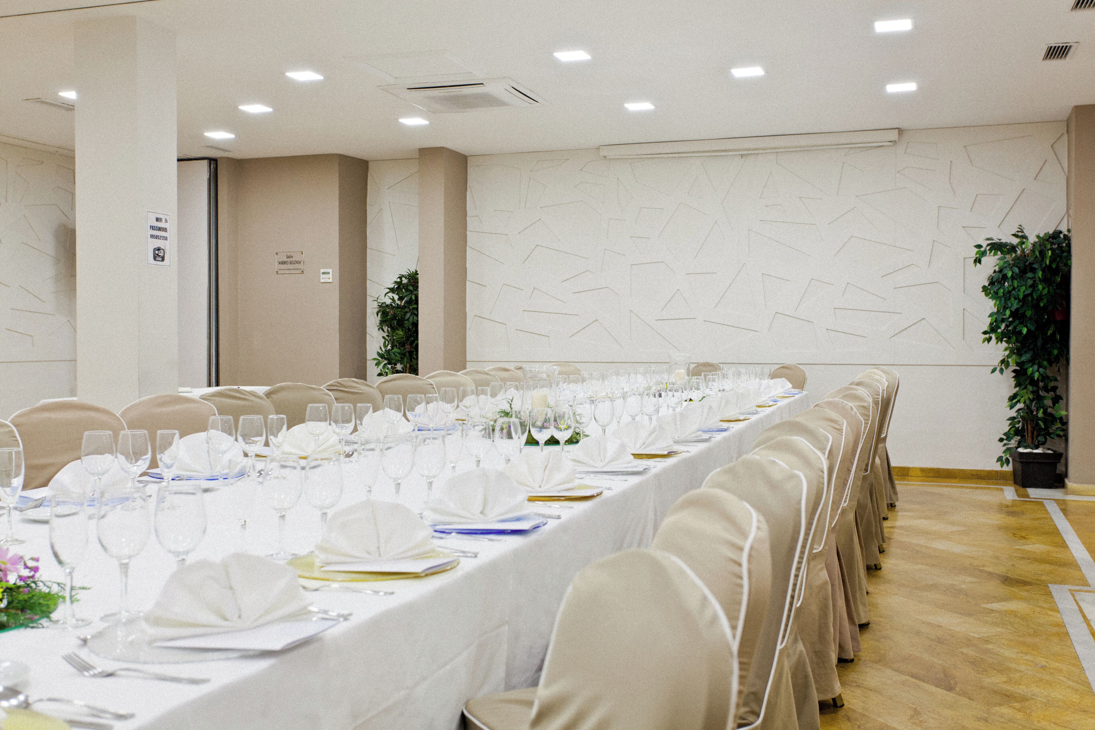 A conference room with long tables set for a meeting, equipped with chairs, tables, and glassware.