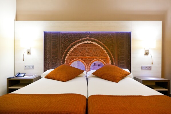 A hotel room with a large bed, two nightstands, a phone, and a decorative headboard.