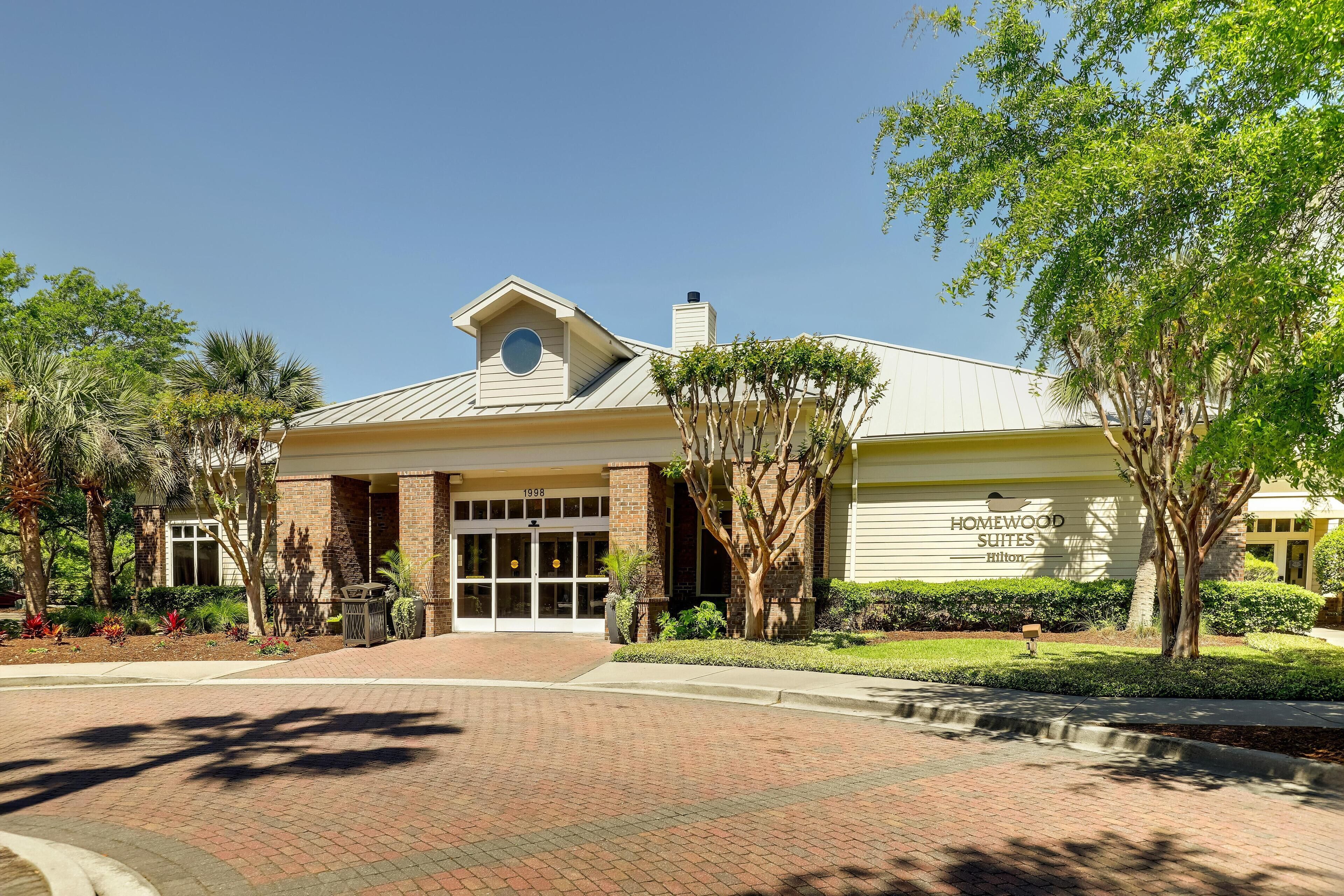 A hotel entrance with a brick facade, large glass doors, and a sign reading "Homewood Suites Hilton".