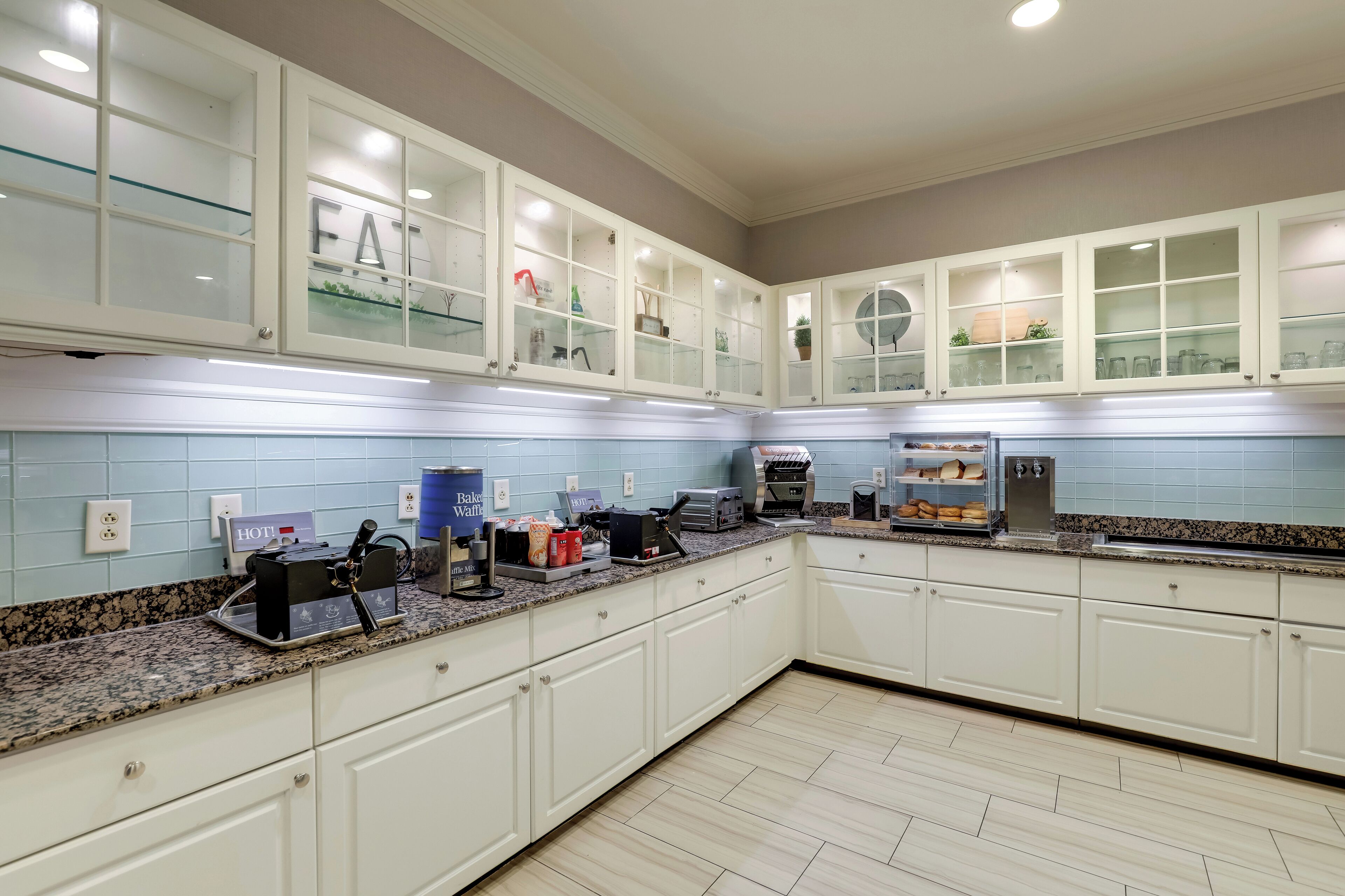 A modern kitchen with white cabinets, a granite countertop, and a built-in oven.