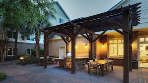 Une terrasse extérieure équipée d’un barbecue, de sièges et d’une pergola.