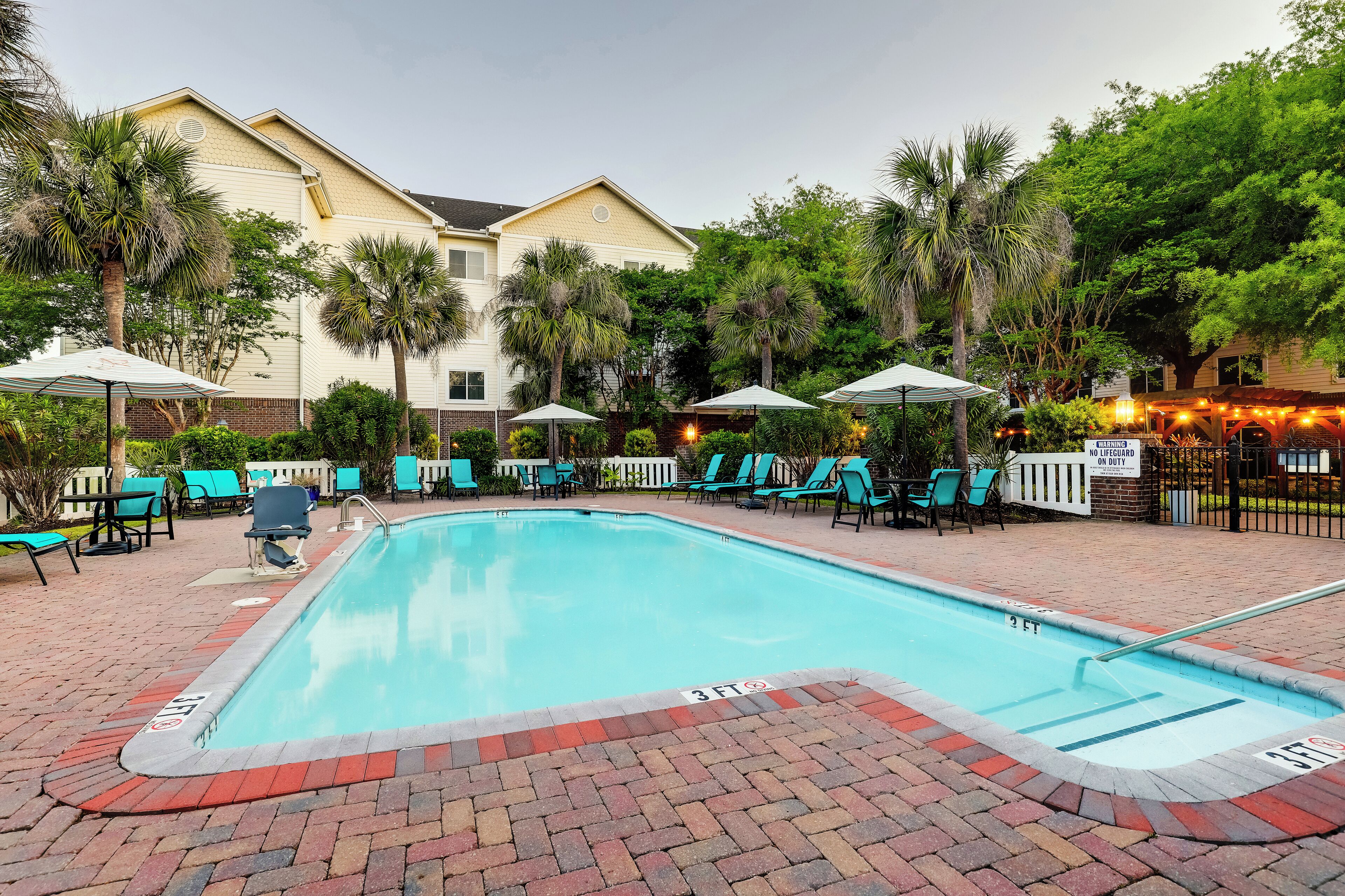 Una piscina al aire libre, sombrillas, sillones reclinables de piscina