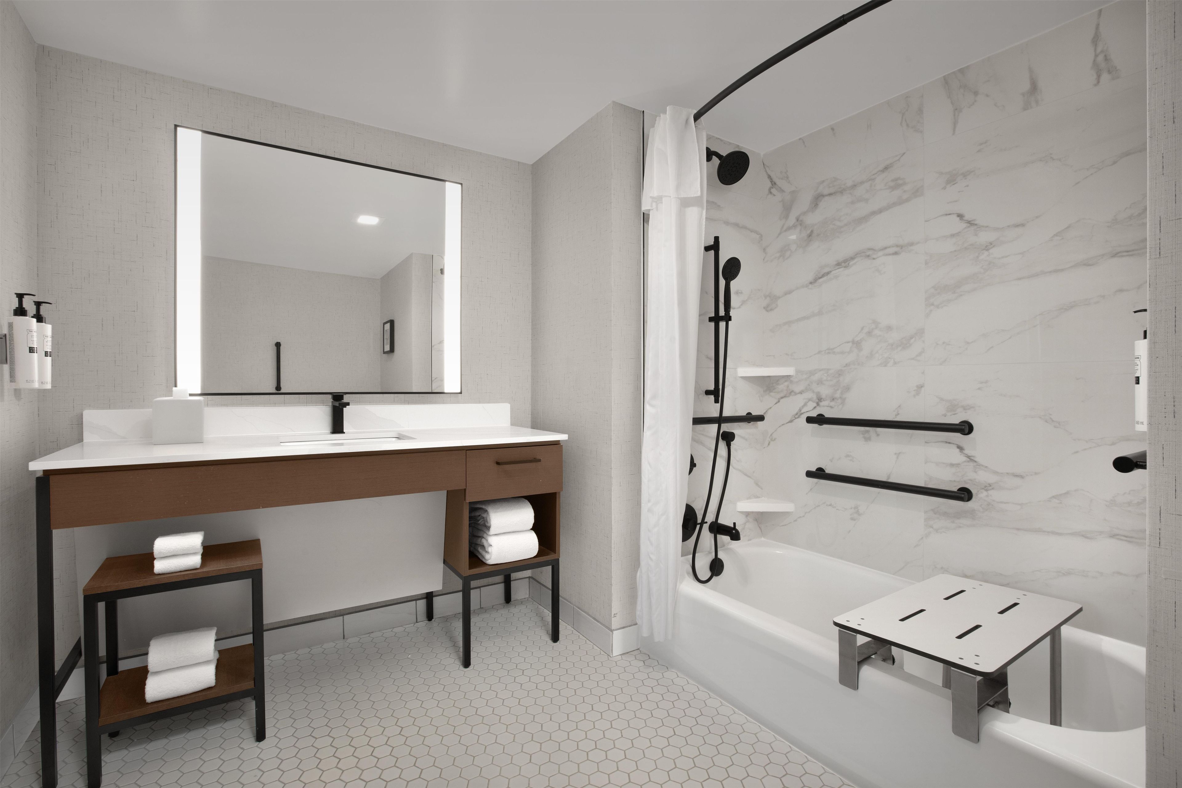 Une salle de bain moderne avec un grand miroir, deux lavabos, une douche et un petit marchepied.