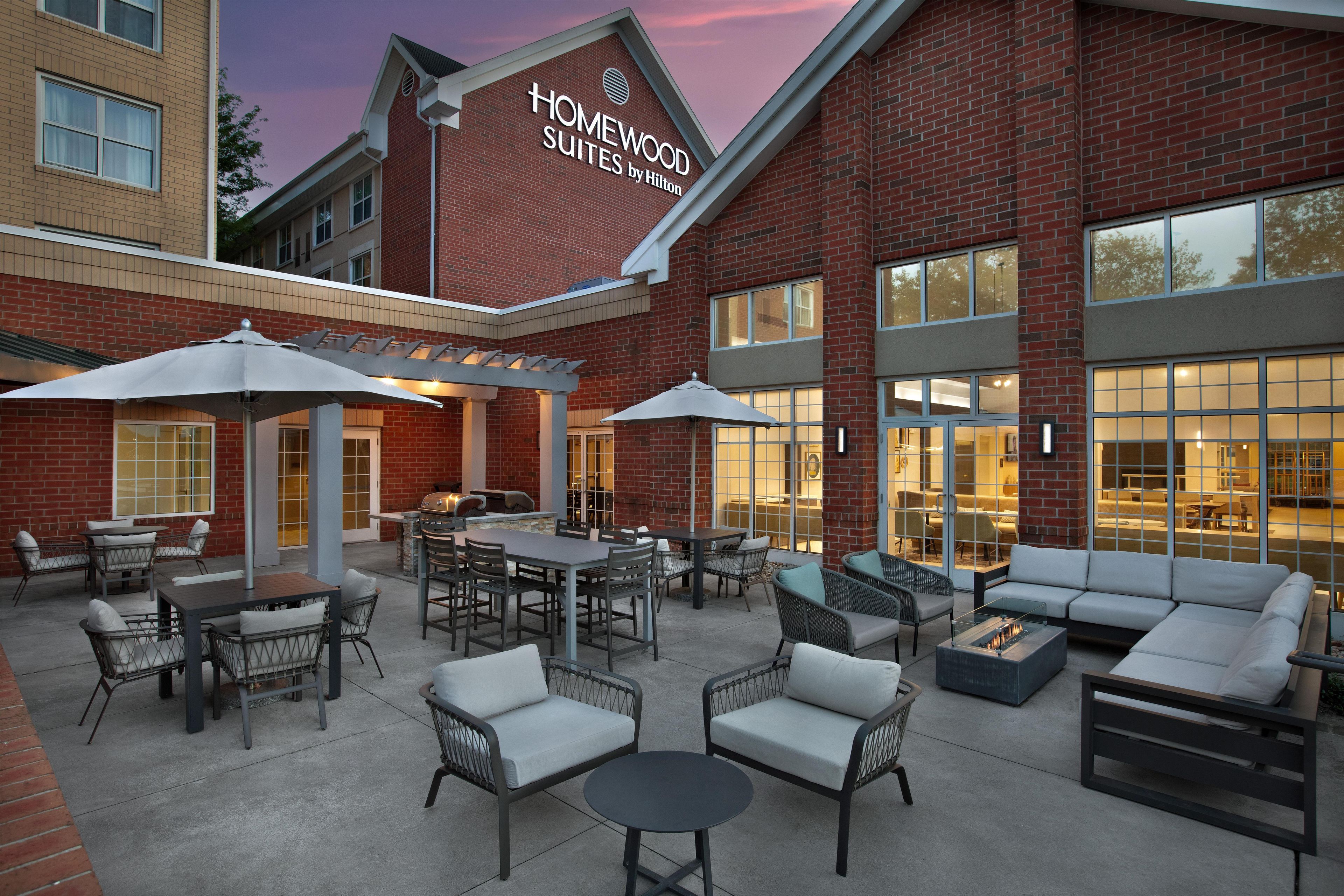 Un patio de hotel con mobiliario exterior, una parrilla y una zona de estar.