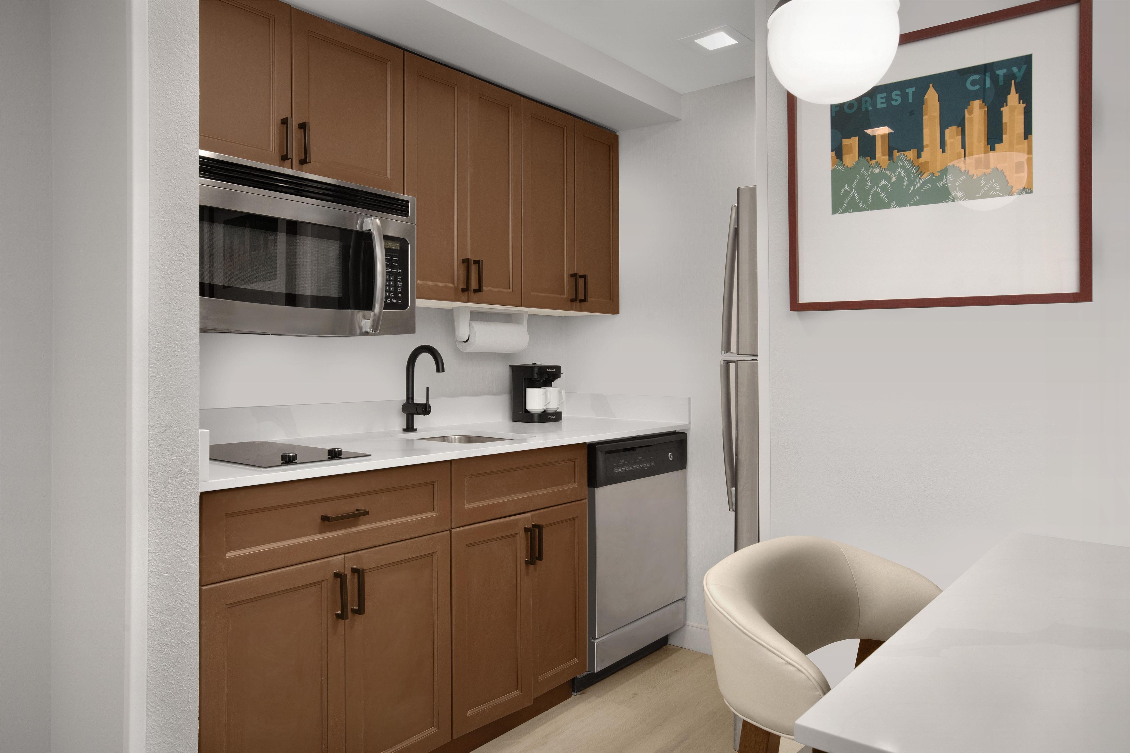 A modern kitchen with wooden cabinets, stainless steel appliances, and a white countertop.