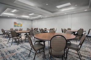A conference room with round tables and wicker chairs, a patterned carpet, and a geometric wall design. - Homewood Suites by Hilton Cleveland-Solon (Solon)