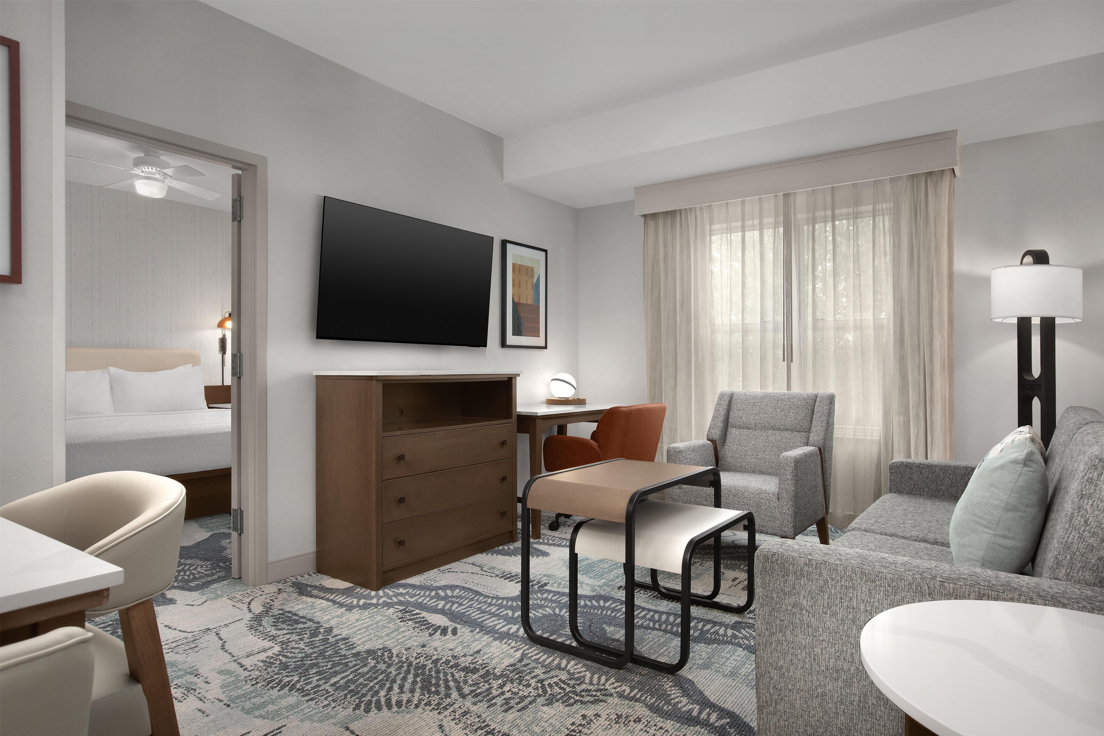 Une chambre d’hôtel équipée d’un lit, d’un bureau, d’une chaise, d’un canapé, d’une télévision et d’une lampe.