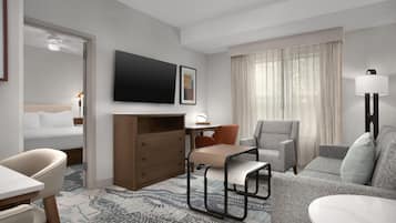 Une chambre d’hôtel équipée d’un lit, d’un bureau, d’une chaise, d’un canapé, d’une télévision et d’une lampe.