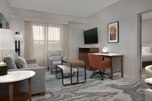 A hotel room with a bed, a desk, a chair, a sofa, a TV, and a lamp. - Homewood Suites by Hilton Cleveland-Solon (Solon)