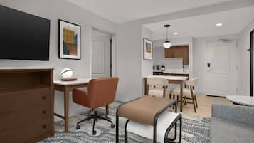 A modern, well-lit room with a desk, office chair, and a dining area with chairs and a table.