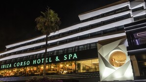 Exterior del Hotel & Spa Ibiza Corso, con un diseño arquitectónico moderno, que presenta varios balcones y un área de spa destacada visible a través de la fachada de vidrio.