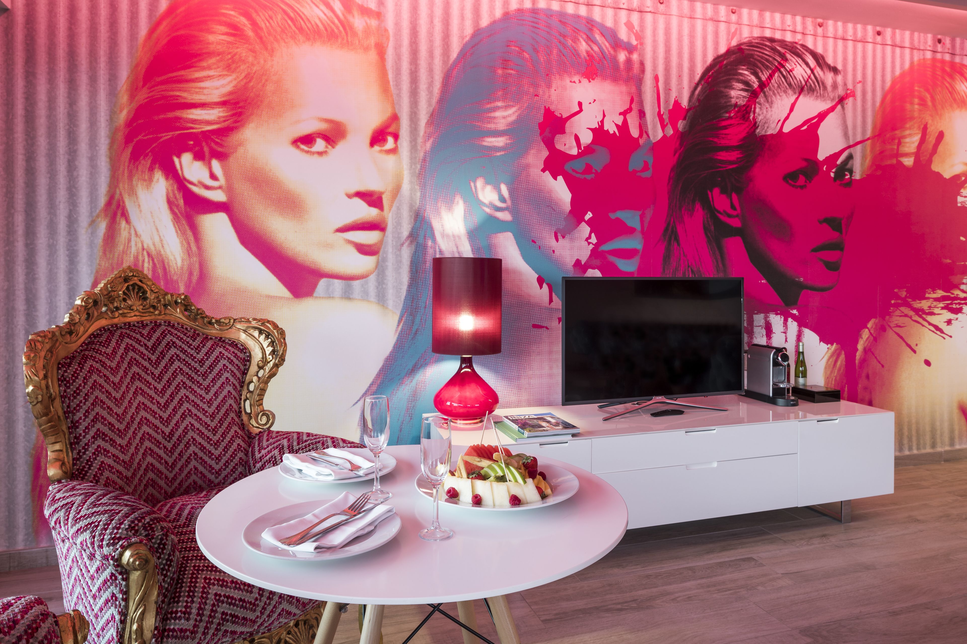 Une pièce moderne avec une table à manger ronde, un téléviseur et une grande fresque murale.