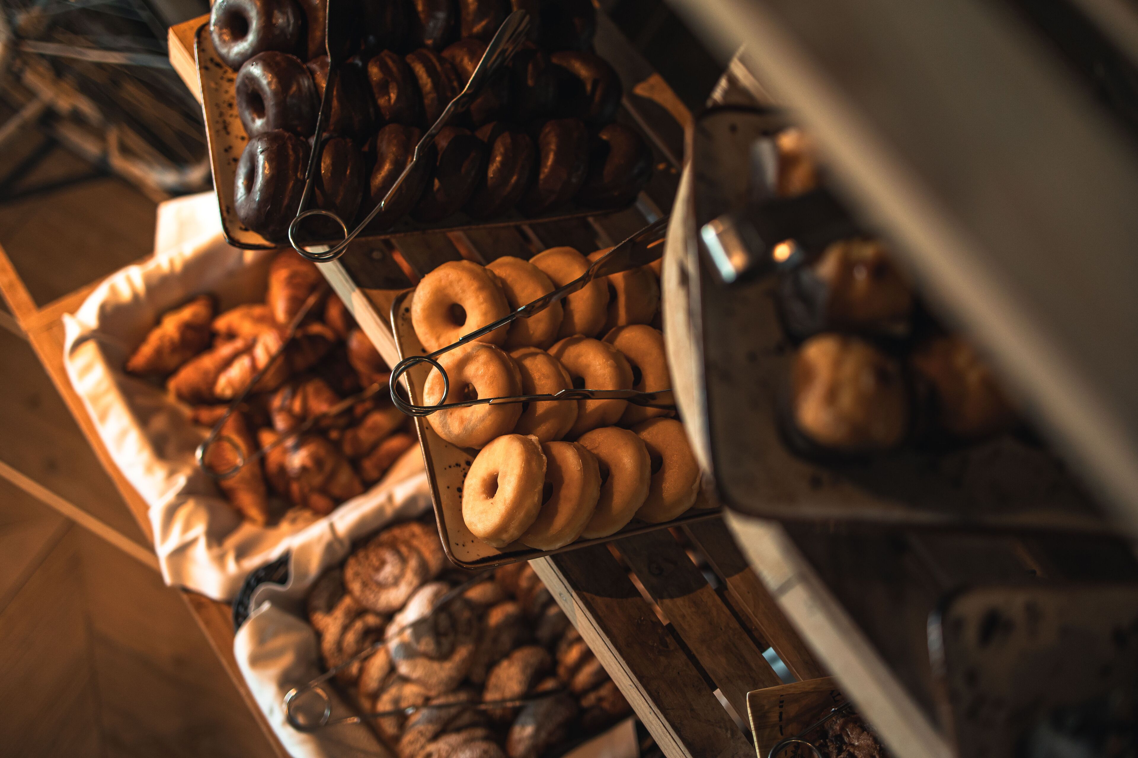 A bakery display with various baked goods, including donuts and pastries, arranged on racks and trays.