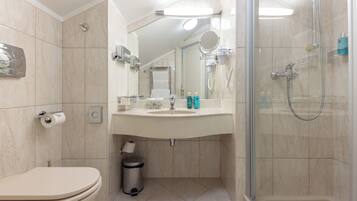 Ein modernes Badezimmer mit Toilette, Waschbecken, Spiegel und Dusche.