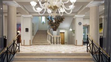 A grand staircase with a chandelier, a floral centerpiece, and a sign for a restaurant.