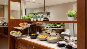 A buffet with various food options, a coffee machine, and potted plants. - My City Hotel (Tallinn)