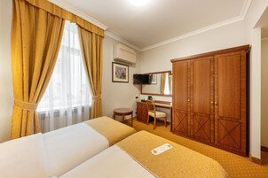 Een hotelkamer met twee bedden, een bureau, een stoel, een kledingkast en een televisie.
