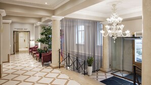 A hotel lobby with a checkered floor, a chandelier, a staircase, and a reception desk. - My City Hotel (Tallinn)