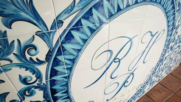 A tiled wall with a decorative pattern and a circular sign with the initials "R & R" and the words "Royal" and "Hotel".
