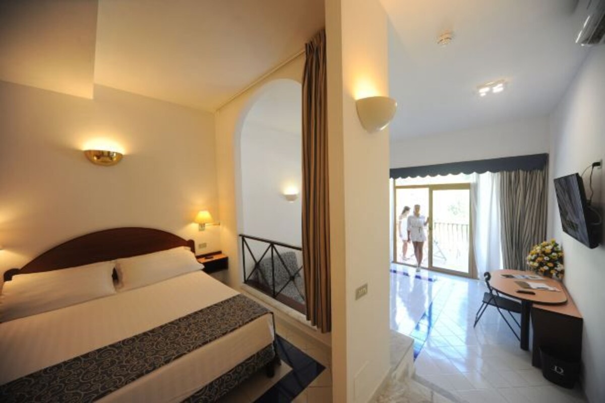 Una habitación de hotel con cama, escritorio y balcón.