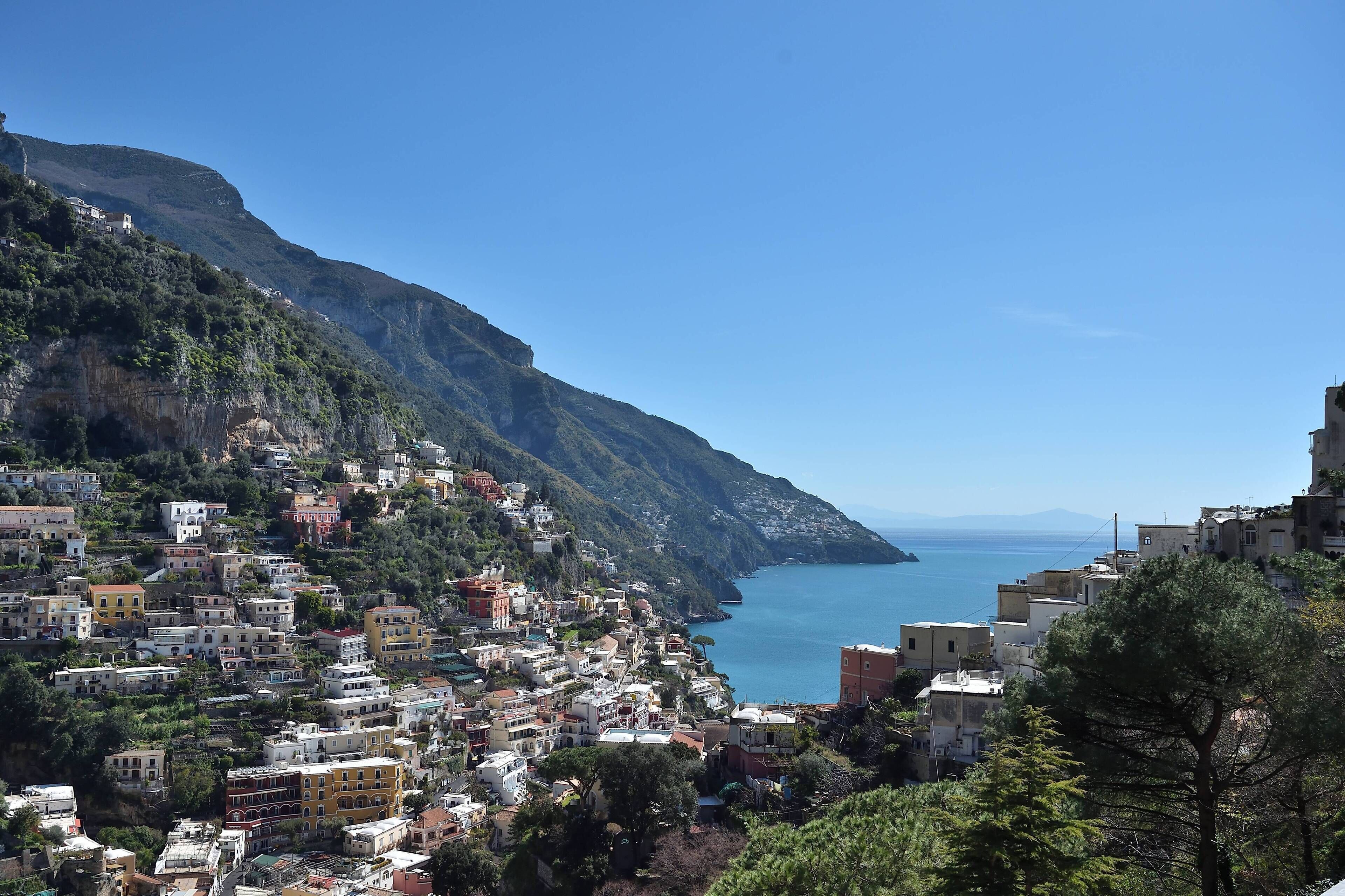 Un pueblo costero con edificios construidos contra una ladera empinada, con vistas al mar.