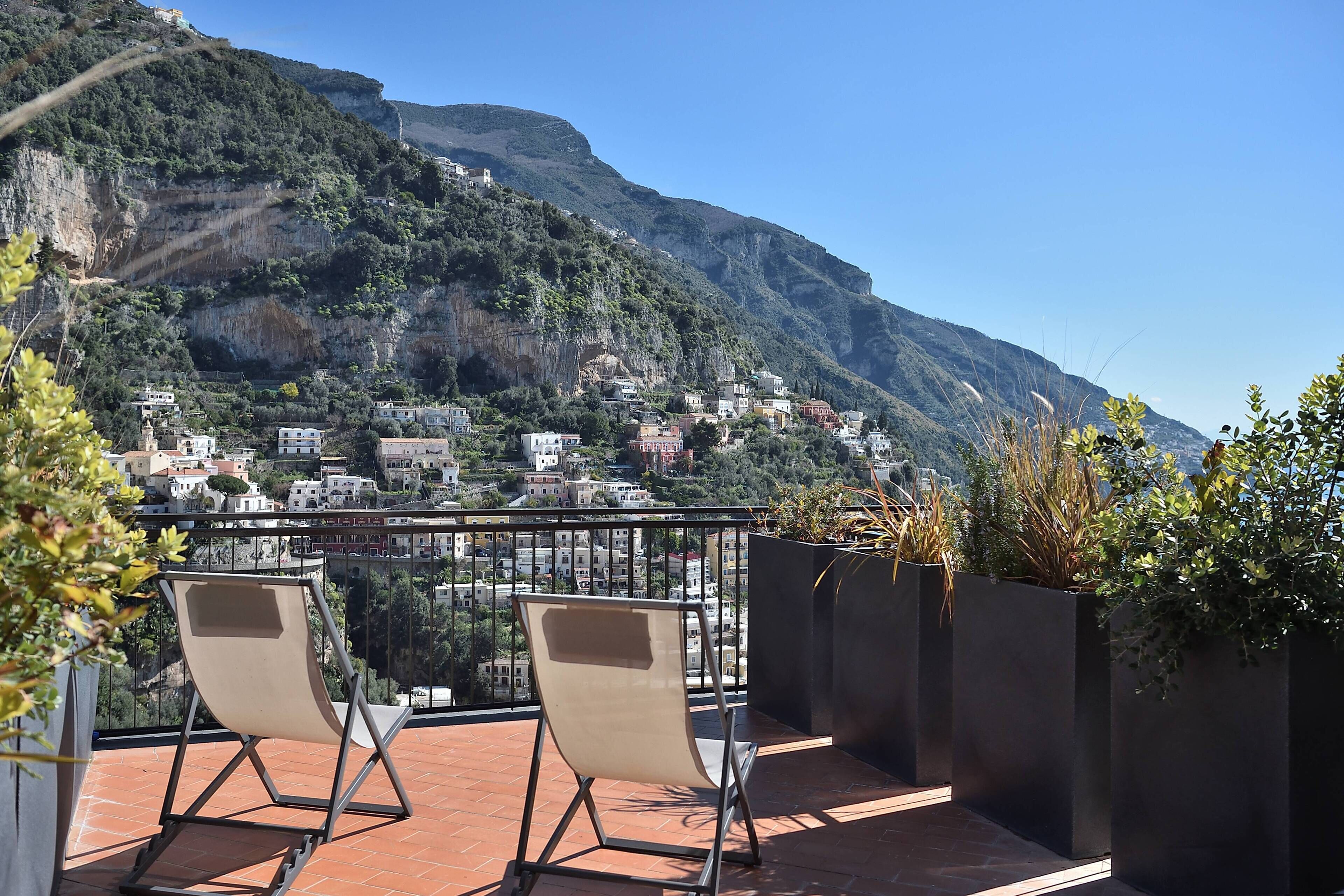 A terrace with two chairs and a view of a hillside village.