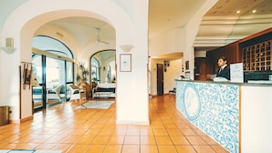 A spacious lobby with a reception desk, a seating area with chairs, and a tiled floor.