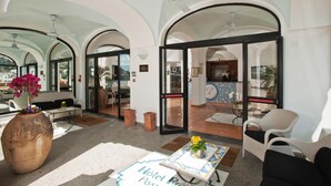 A hotel lobby with arched ceilings, a reception desk, seating areas, and a large vase with flowers. - Hotel Royal Positano (Positano)