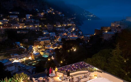 A coastal town at night with illuminated buildings and a view of the sea.