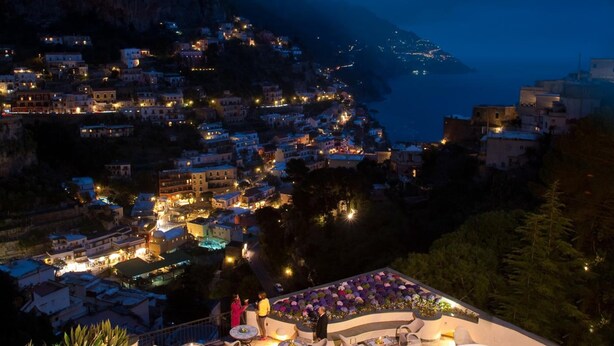 A coastal town at night with illuminated buildings and a view of the sea. - Hotel Royal Positano (Positano)